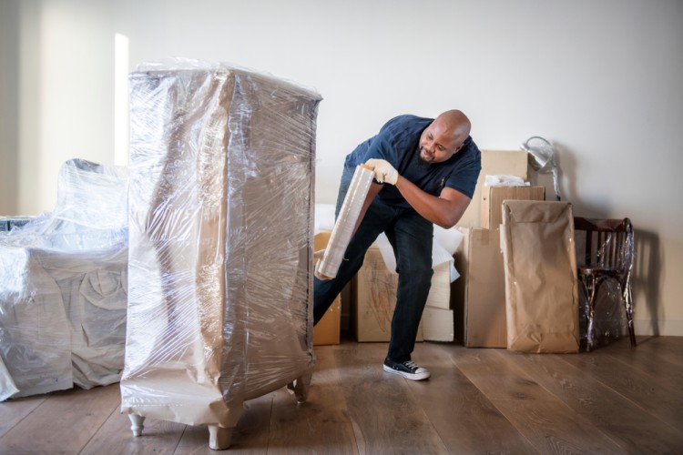 Movers wrapping and packing furniture for a move.